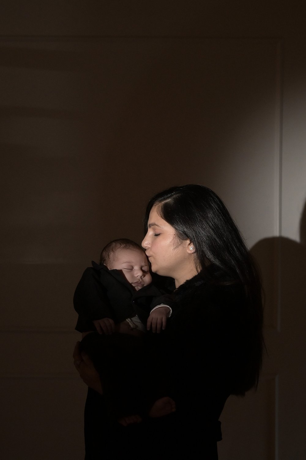 Mother holding and kissing her newborn baby